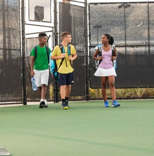 Three young kids walking on the tennis court